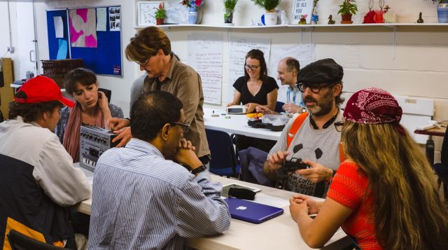 A photo of a room full of people fixing electronics