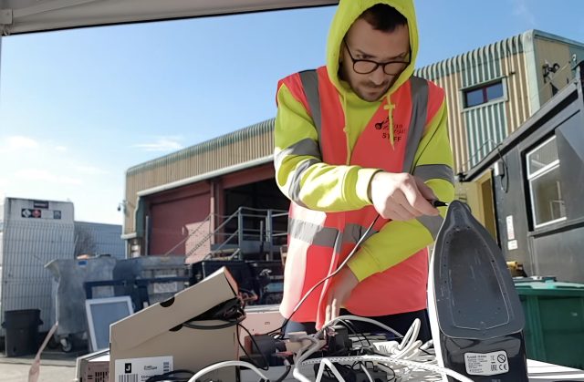 A man in a flourescent jacket testing an iron